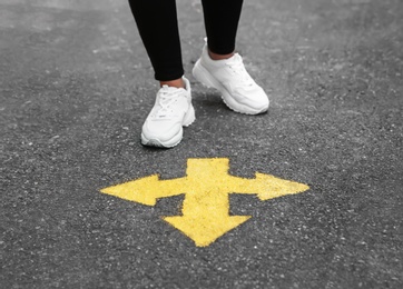 Woman standing near arrow on asphalt, closeup Photo of Woman standing near arrow on asphalt, closeup