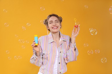 Photo of Young woman blowing soap bubbles on yellow background
