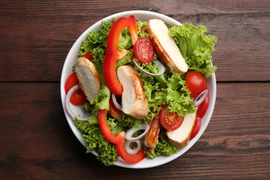 Delicious salad with chicken and vegetables on wooden table, top view Photo of Delicious salad with chicken and vegetables on wooden table, top view