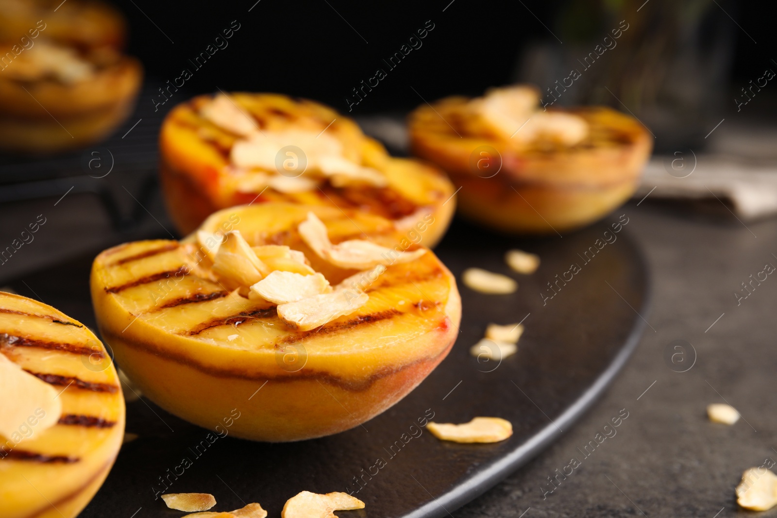 Delicious grilled peaches with almond flakes on grey table, closeup Photo of Delicious grilled peaches with almond flakes on grey table, closeup