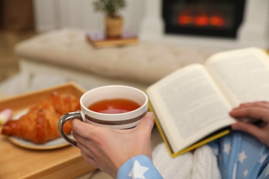 Woman with cup of tea and book resting at home, closeup Photo of Woman with cup of tea and book resting at home, closeup