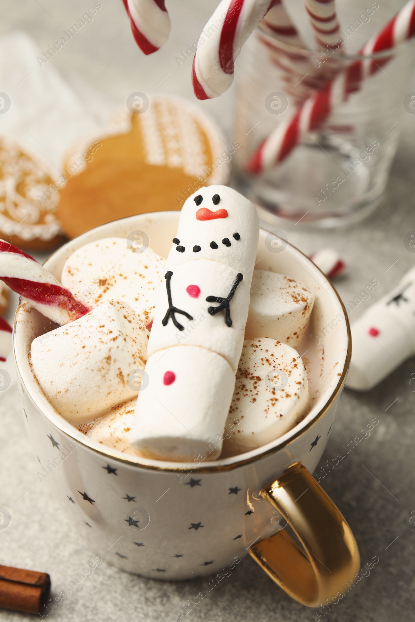 Funny marshmallow snowman in cup of hot drink on light grey table, above view Photo of Funny marshmallow snowman in cup of hot drink on light grey table, above view