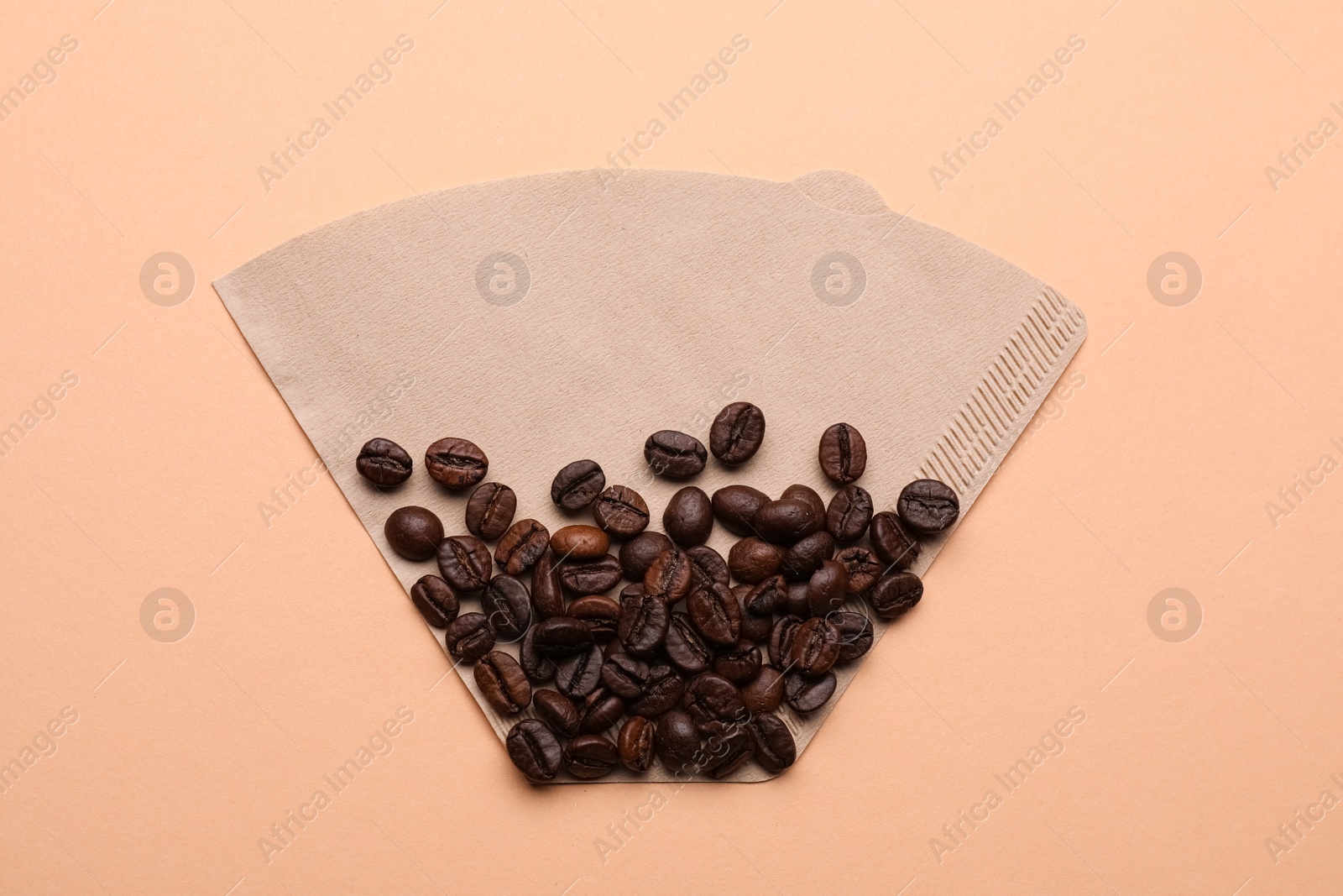 Paper coffee filter and beans on beige background, top view Photo of Paper coffee filter and beans on beige background, top view
