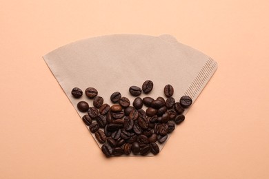 Paper coffee filter and beans on beige background, top view Photo of Paper coffee filter and beans on beige background, top view