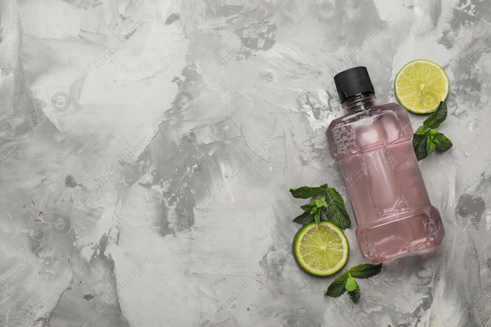 Mouthwash, mint and lime on grey marble background, flat lay. Space for text Photo of Mouthwash, mint and lime on grey marble background, flat lay. Space for text