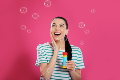 Young woman having fun with soap bubbles on pink background Photo of Young woman having fun with soap bubbles on pink background