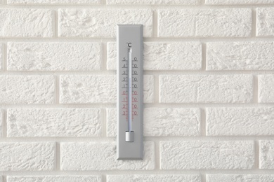 Weather thermometer hanging on white brick wall Photo of Weather thermometer hanging on white brick wall