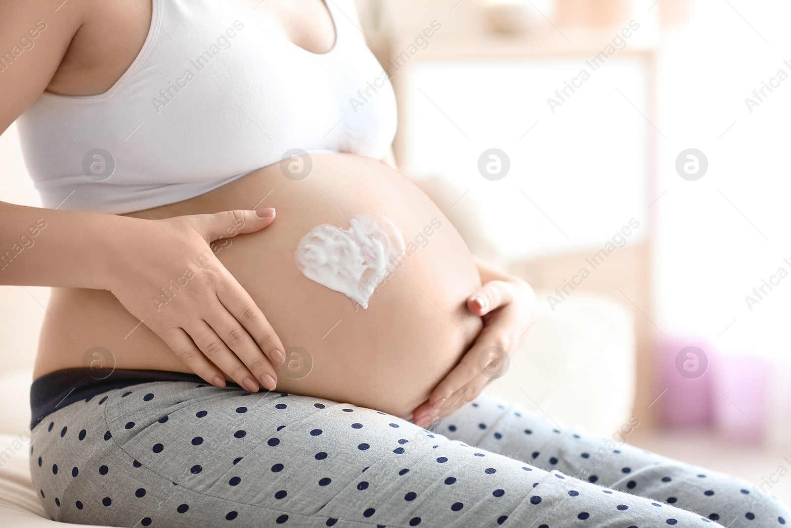 Heart painted with cream on pregnant woman's belly against blurred background, closeup Photo of Heart painted with cream on pregnant woman's belly against blurred background, closeup