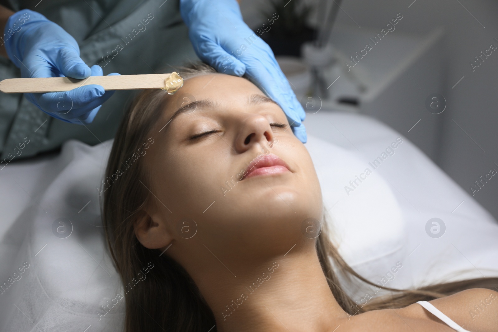 Young woman undergoing hair removal procedure on face with sugaring paste in salon Photo of Young woman undergoing hair removal procedure on face with sugaring paste in salon