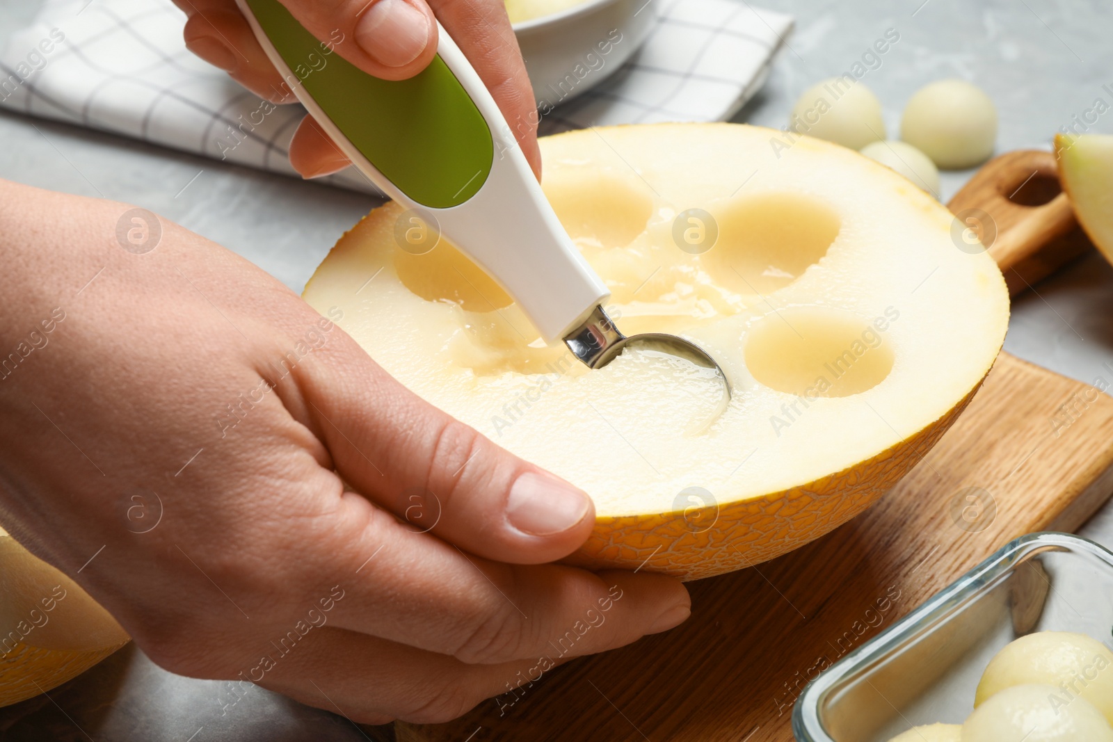 Woman making melon balls at table, closeup Photo of Woman making melon balls at table, closeup