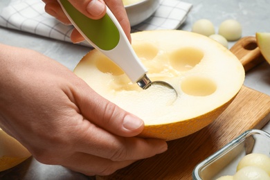Woman making melon balls at table, closeup Photo of Woman making melon balls at table, closeup