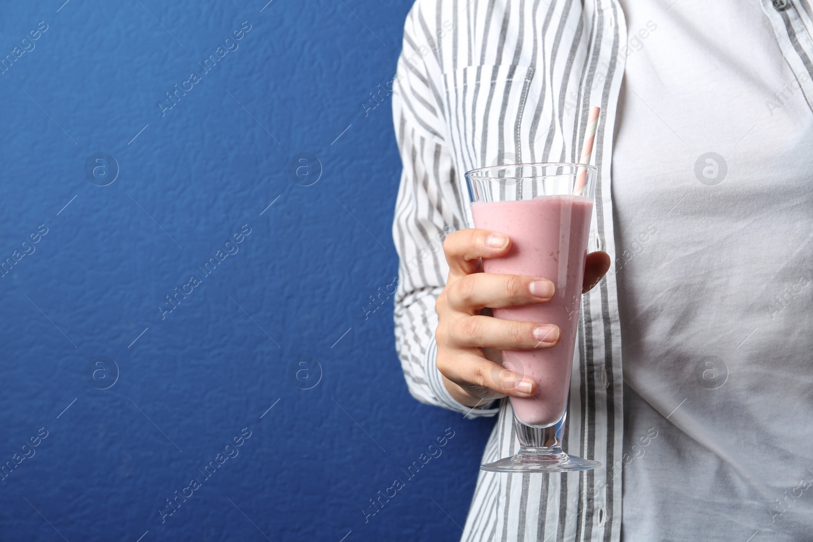 Woman with glass of tasty smoothie on blue background, closeup. Space for text Image of Woman with glass of tasty smoothie on blue background, closeup. Space for text
