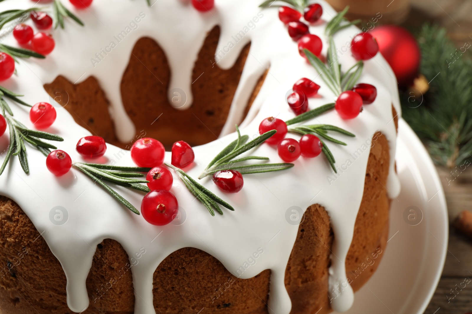 Photo of Traditional Christmas cake decorated with glaze, pomegranate seeds, cranberries and rosemary, closeup