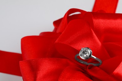 Beautiful red bow and engagement ring on white background, closeup Photo of Beautiful red bow and engagement ring on white background, closeup