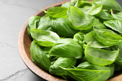 Fresh basil leaves in wooden bowl, closeup Photo of Fresh basil leaves in wooden bowl, closeup