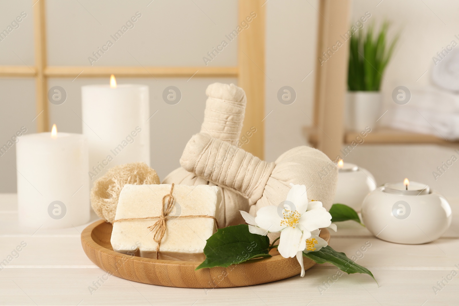 Composition with beautiful jasmine flowers and burning candles on white wooden table indoors Photo of Composition with beautiful jasmine flowers and burning candles on white wooden table indoors