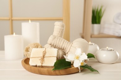 Composition with beautiful jasmine flowers and burning candles on white wooden table indoors Photo of Composition with beautiful jasmine flowers and burning candles on white wooden table indoors