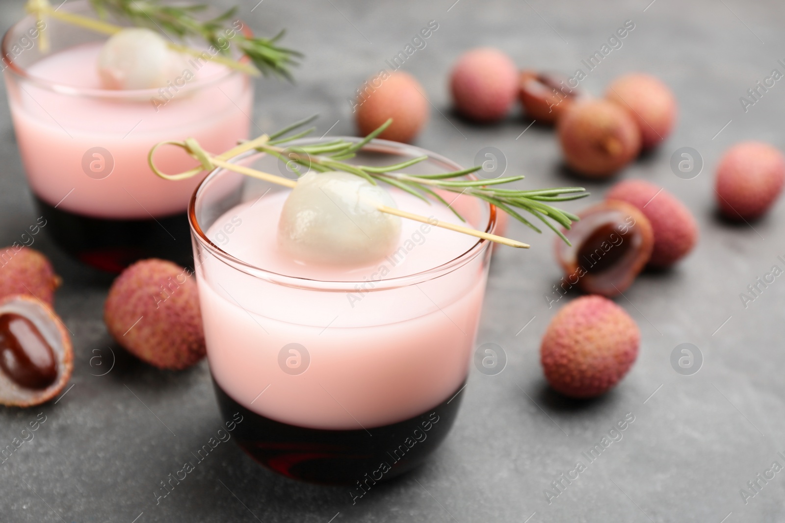 Lychee cocktail with fresh fruits and rosemary on grey table, closeup Photo of Lychee cocktail with fresh fruits and rosemary on grey table, closeup