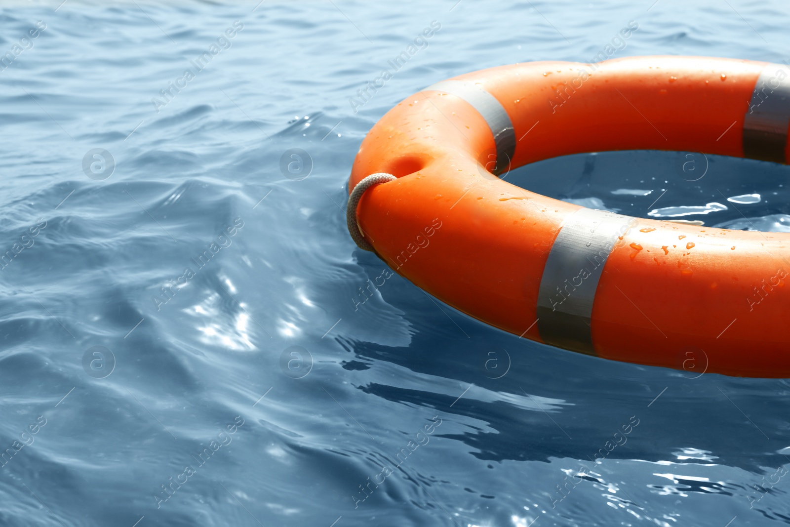 Orange life buoy floating in sea, closeup. Emergency rescue equipment Photo of Orange life buoy floating in sea, closeup. Emergency rescue equipment