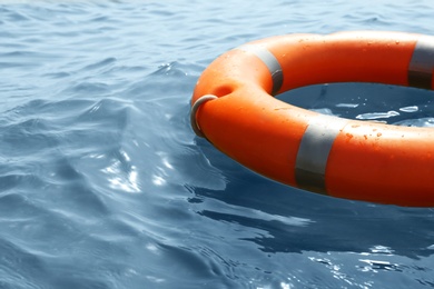 Orange life buoy floating in sea, closeup. Emergency rescue equipment Photo of Orange life buoy floating in sea, closeup. Emergency rescue equipment