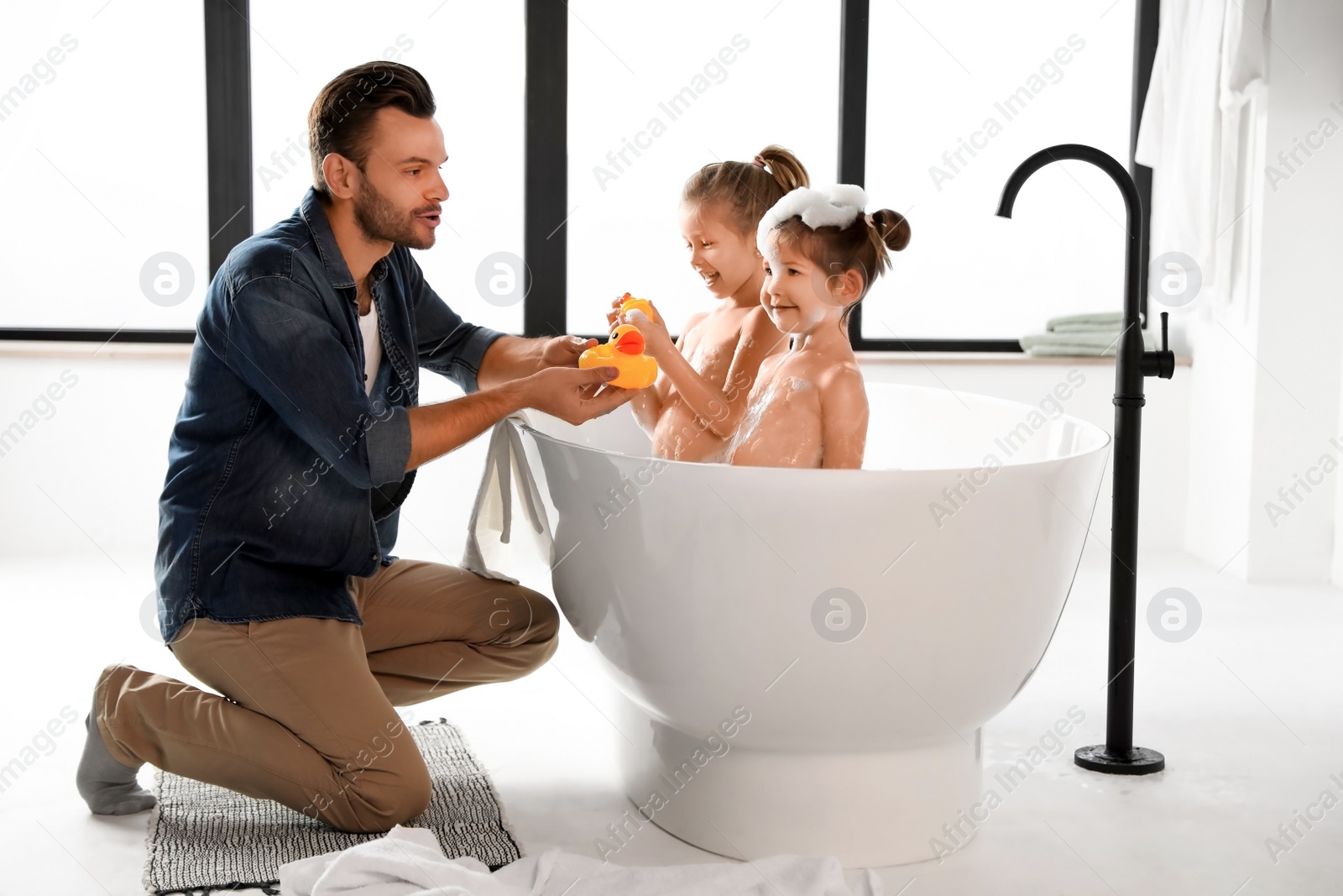 Photo of Young father with little daughters in bathroom