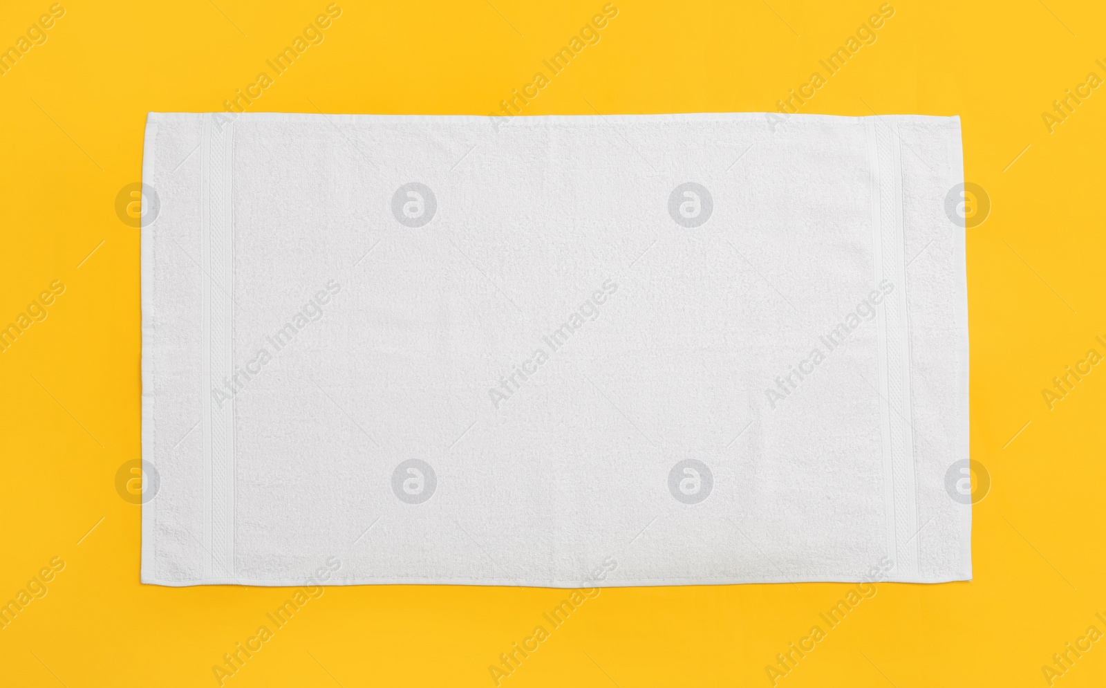 White beach towel on yellow background, top view Photo of White beach towel on yellow background, top view