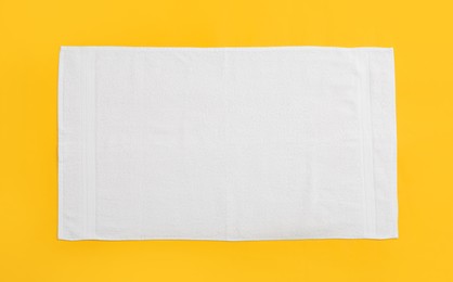 White beach towel on yellow background, top view Photo of White beach towel on yellow background, top view