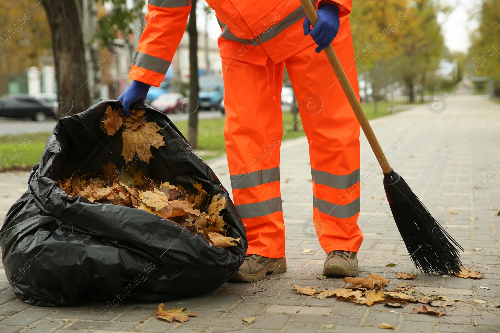 Worker cleaning street from fallen leaves on autumn day, closeup Photo of Worker cleaning street from fallen leaves on autumn day, closeup