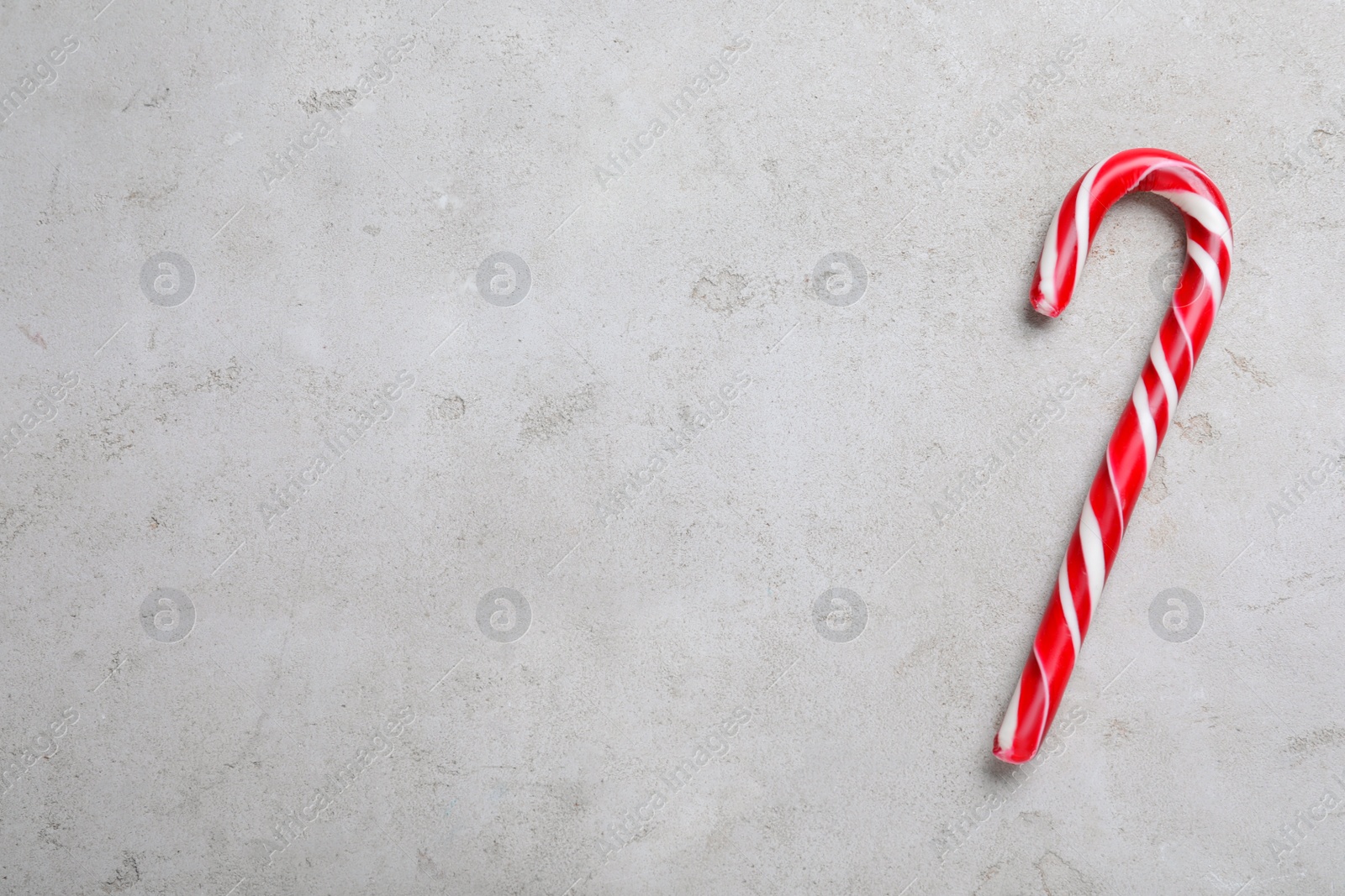 Photo of Sweet Christmas candy cane on grey background, top view. Space for text