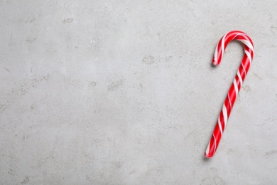 Photo of Sweet Christmas candy cane on grey background, top view. Space for text