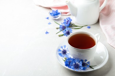 Cup of tea and cornflowers on light table. Space for text Photo of Cup of tea and cornflowers on light table. Space for text