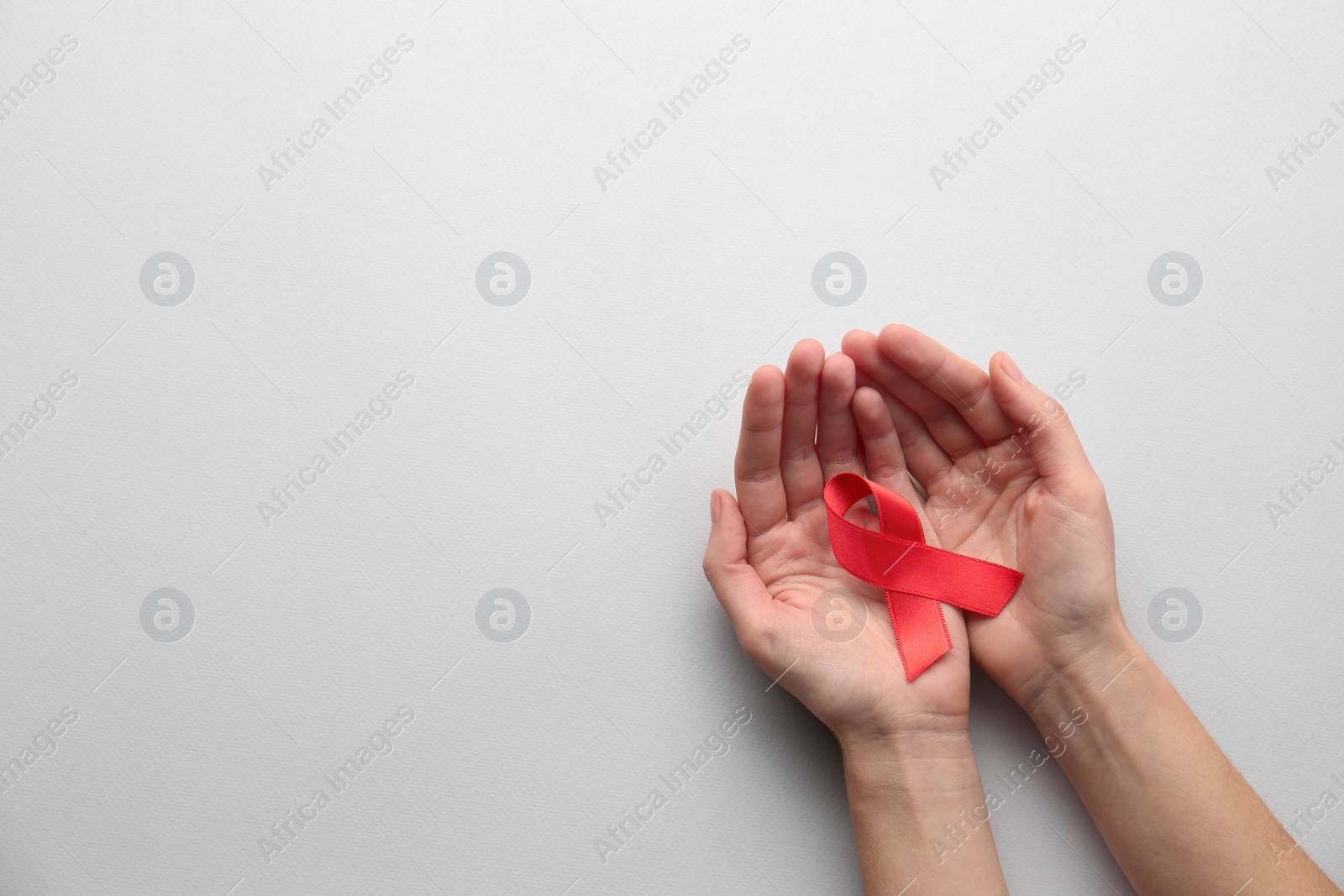Woman holding red awareness ribbon on white background, top view with space for text. World AIDS disease day Photo of Woman holding red awareness ribbon on white background, top view with space for text. World AIDS disease day