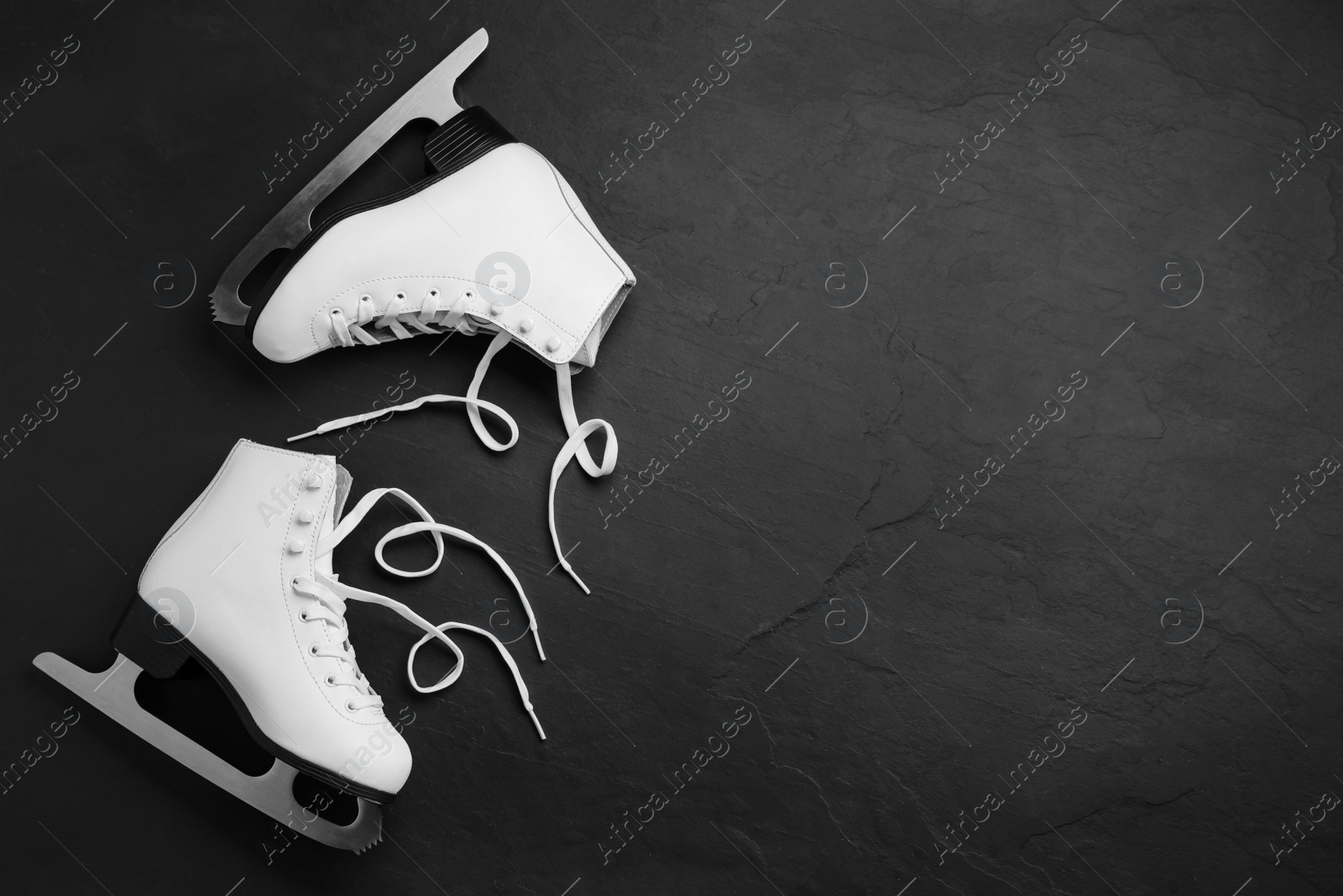 Pair of white ice skates on black stone background, top view. Space for text Photo of Pair of white ice skates on black stone background, top view. Space for text
