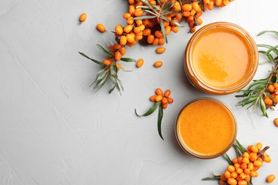 Delicious sea buckthorn jam and fresh berries on light grey table, flat lay. Space for text Photo of Delicious sea buckthorn jam and fresh berries on light grey table, flat lay. Space for text
