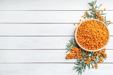 Fresh ripe sea buckthorn on white wooden table, flat lay. Space for text Photo of Fresh ripe sea buckthorn on white wooden table, flat lay. Space for text