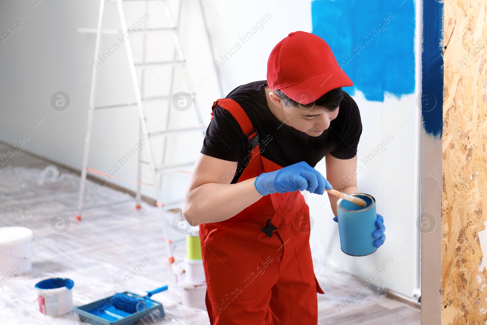 Male decorator painting wall with brush indoors Photo of Male decorator painting wall with brush indoors
