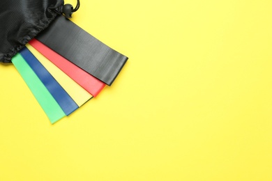 Set of fitness elastic bands in bag on yellow background, top view. Space for text Photo of Set of fitness elastic bands in bag on yellow background, top view. Space for text
