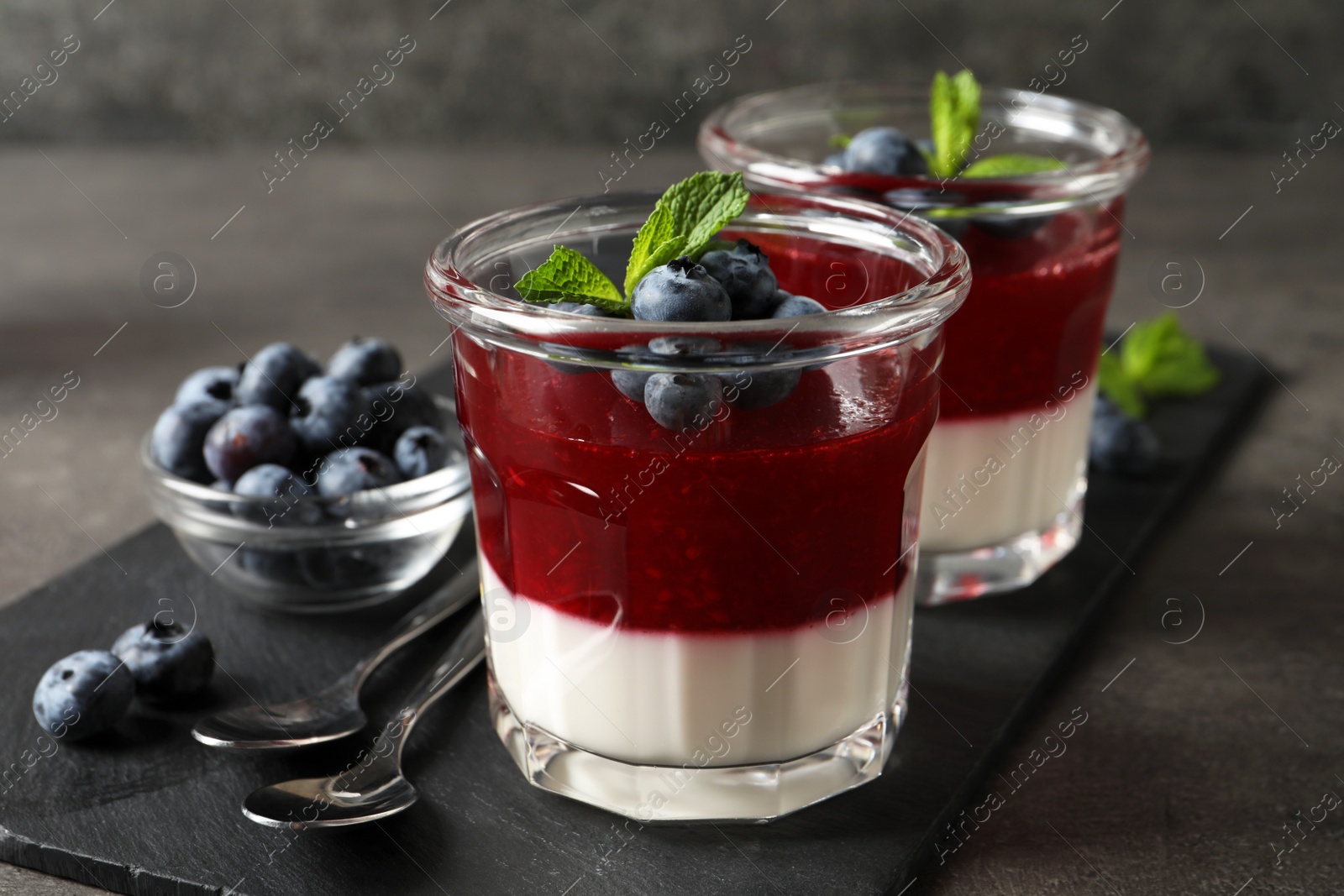 Delicious panna cotta with fruit coulis and fresh blueberries served on grey table Photo of Delicious panna cotta with fruit coulis and fresh blueberries served on grey table