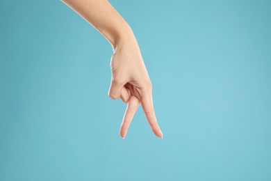 Woman imitating walk with hand on light blue background, closeup. Finger gesture Photo of Woman imitating walk with hand on light blue background, closeup. Finger gesture