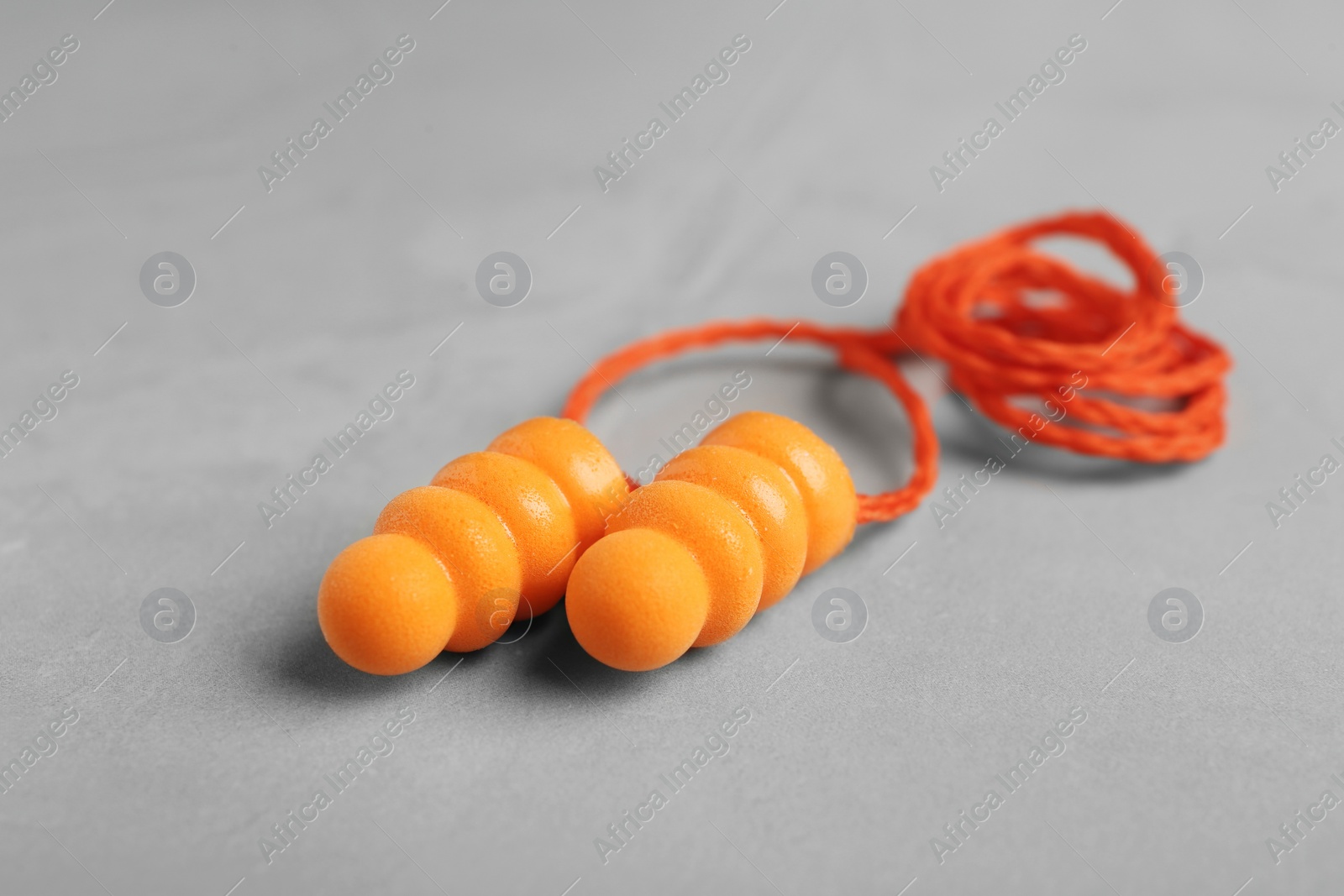 Pair of orange ear plugs with cord on grey background, closeup Photo of Pair of orange ear plugs with cord on grey background, closeup