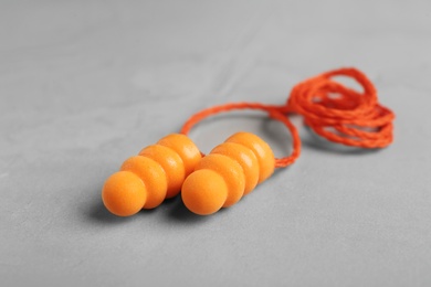 Pair of orange ear plugs with cord on grey background, closeup Photo of Pair of orange ear plugs with cord on grey background, closeup