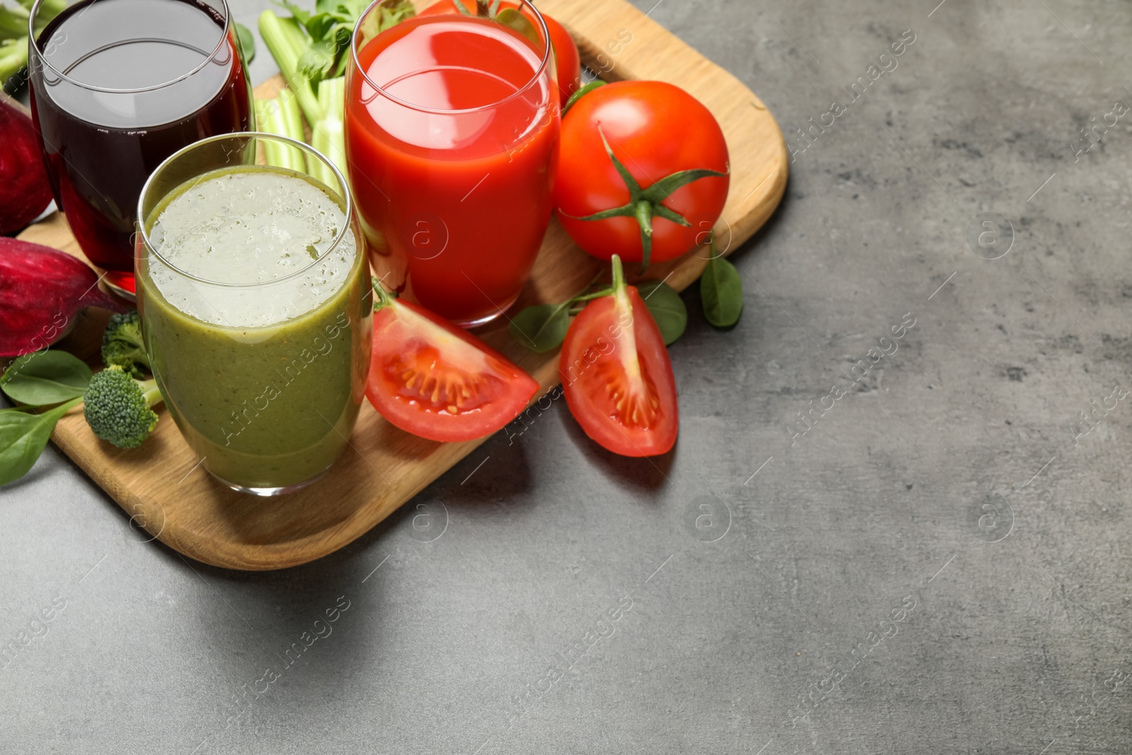 Delicious vegetable juices and fresh ingredients on grey table. Space for text Photo of Delicious vegetable juices and fresh ingredients on grey table. Space for text