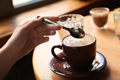 Photo of Woman with aromatic coffee at table in cafe, closeup
