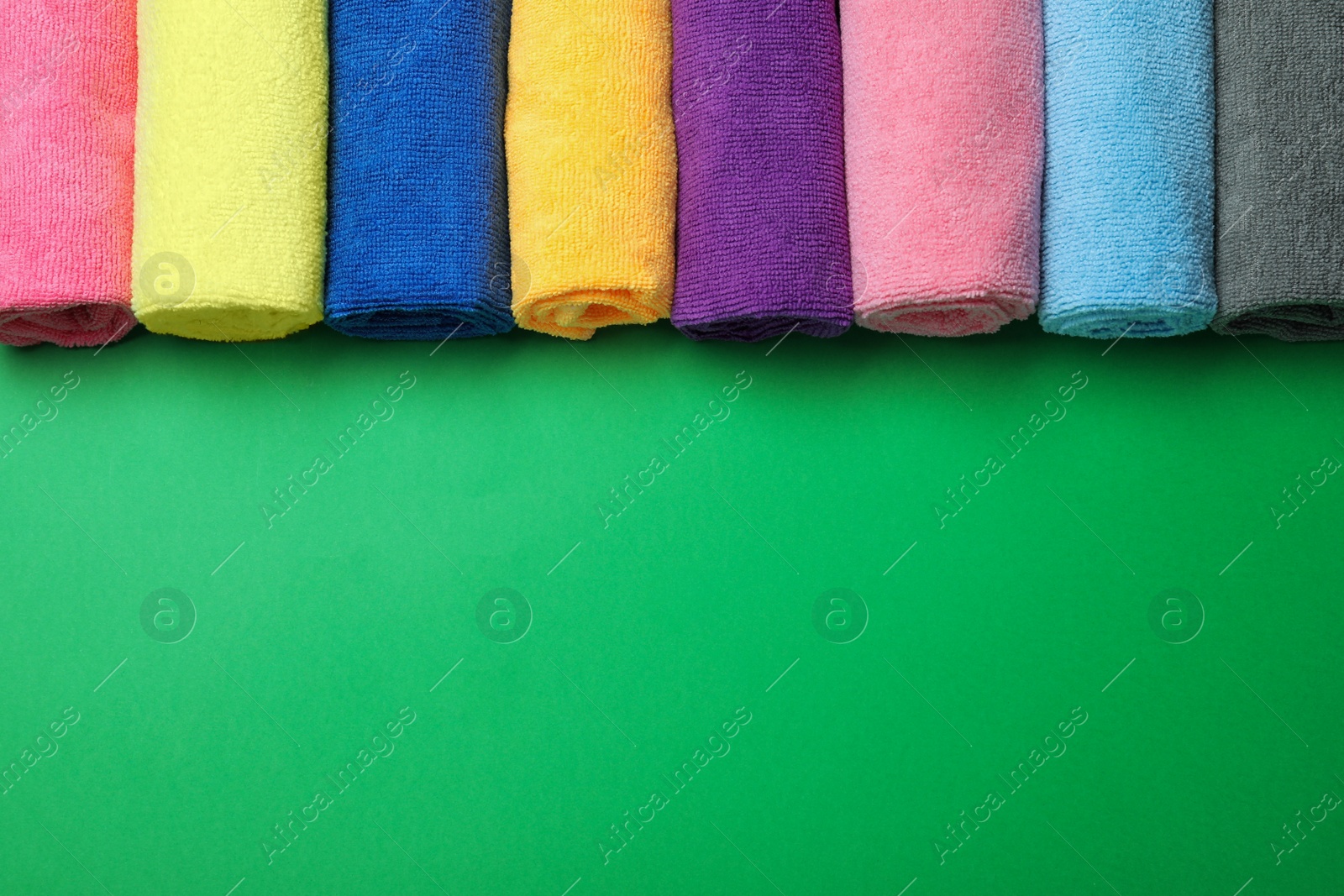 Many colorful microfiber cloths on green background, flat lay. Space for text Photo of Many colorful microfiber cloths on green background, flat lay. Space for text