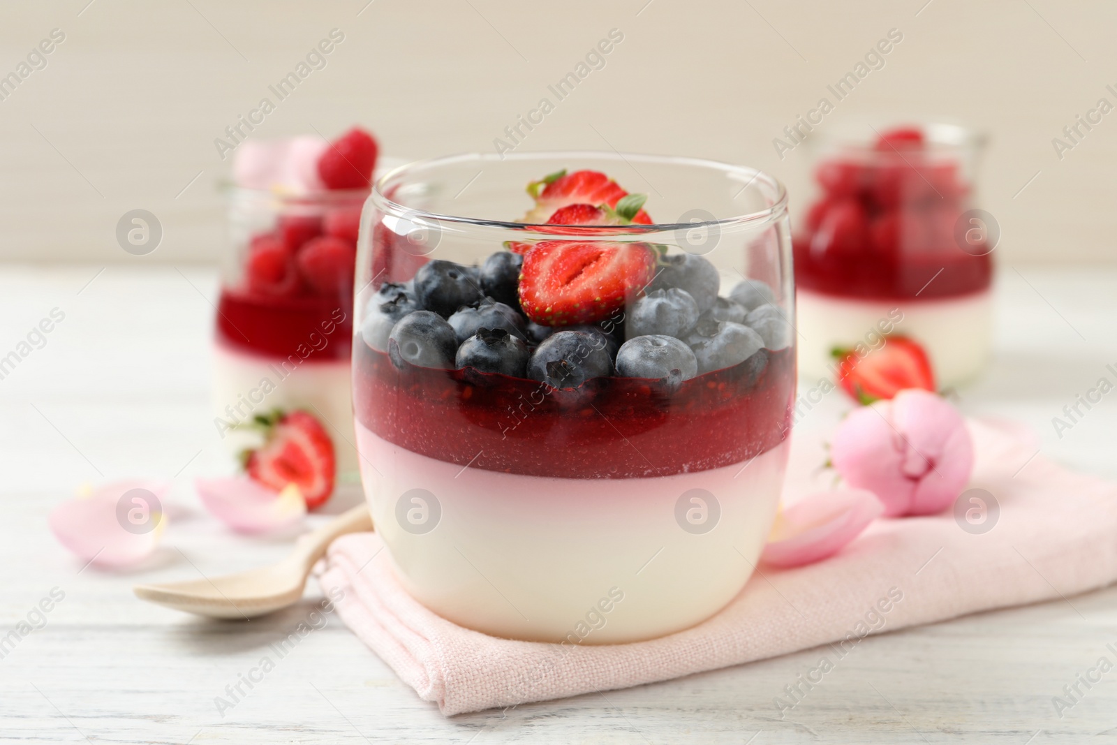 Delicious panna cotta with berries on white wooden table Photo of Delicious panna cotta with berries on white wooden table