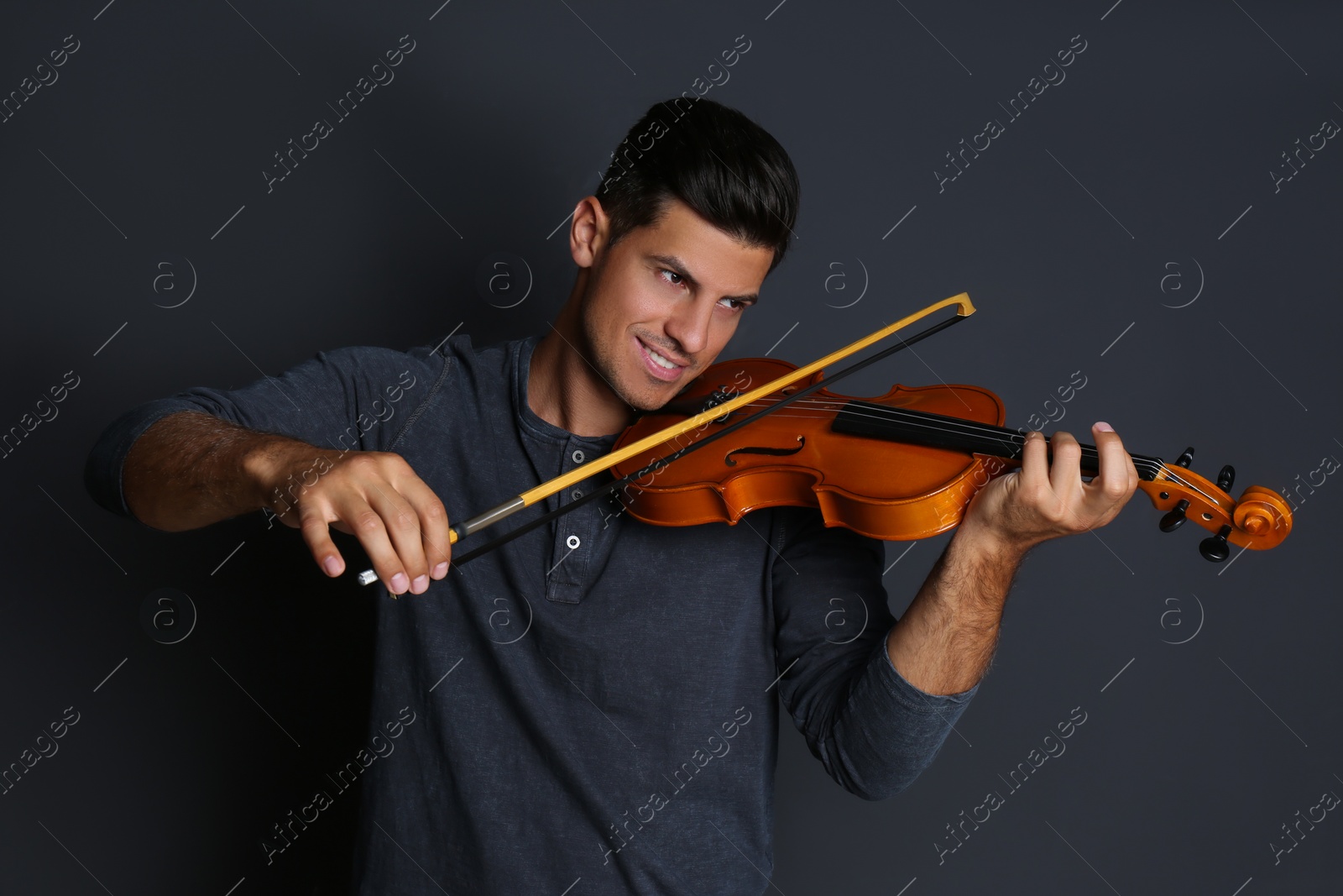 Happy man playing violin on black background Photo of Happy man playing violin on black background