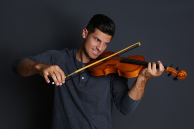 Happy man playing violin on black background Photo of Happy man playing violin on black background