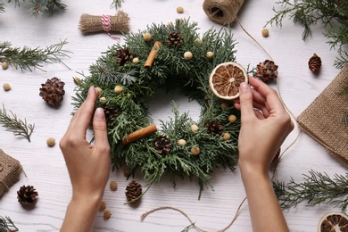 Florist making beautiful Christmas wreath at white wooden table, top view Photo of Florist making beautiful Christmas wreath at white wooden table, top view