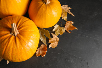 Ripe pumpkins and autumn leaves on black table, above view Photo of Ripe pumpkins and autumn leaves on black table, above view
