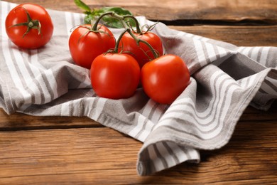 Kitchen towel and fresh tomatoes on wooden table Photo of Kitchen towel and fresh tomatoes on wooden table